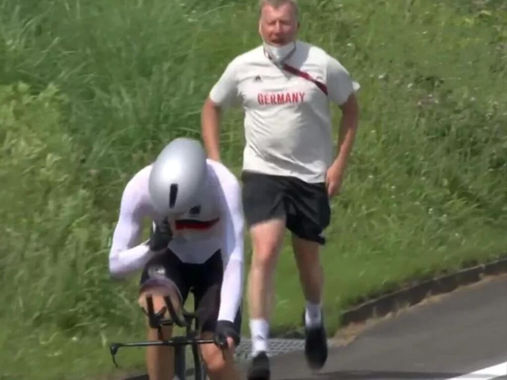 A person riding a bike and a person walking behind