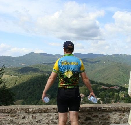 Mike in a yellow-and-light blue cycling uniform looking at a mountain range