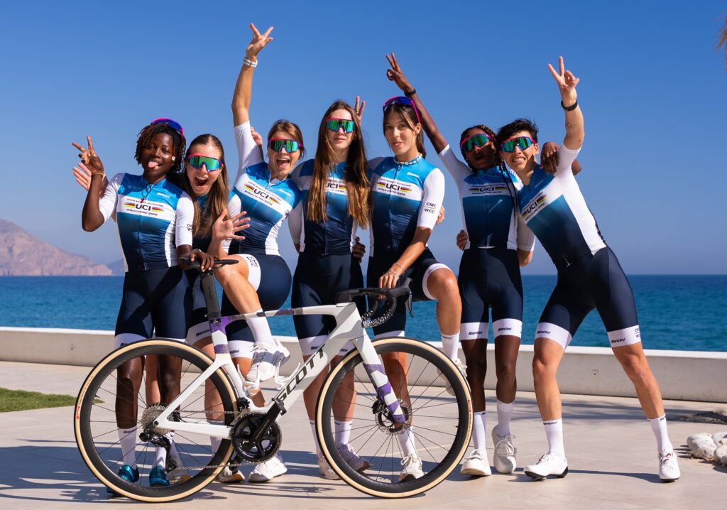 Group of cyclists posing by the sea with their bikes, celebrating.